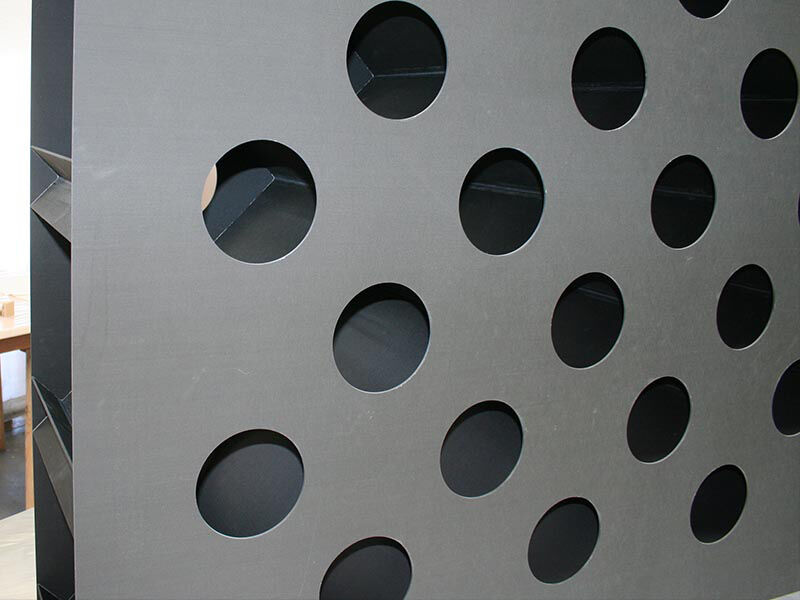 Exterior detail image of the near zero CTE antenna segment. Surface exterior panel has circular holes in a grid pattern across its surface. The interior grid structure is visible through the holes.